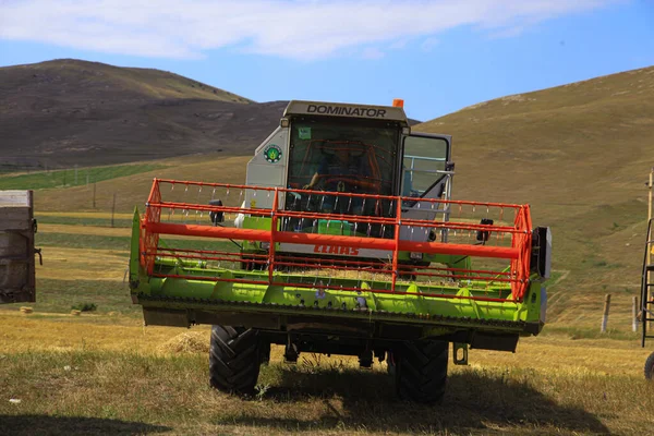 A machine gathering harvest in the farmland.